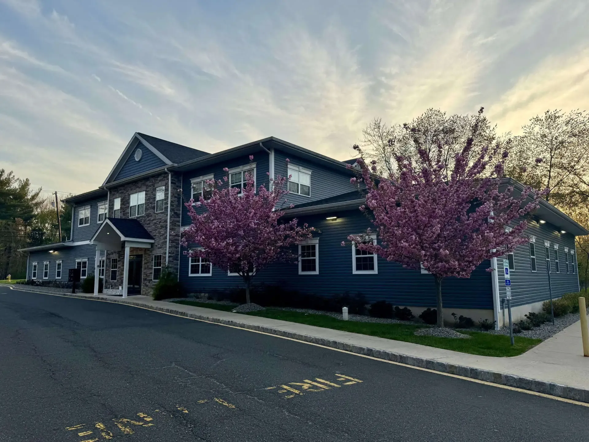 The exterior of the Limitless Spine and Joint Care office building in Morganville, NJ, with cherry blossoms at sunset